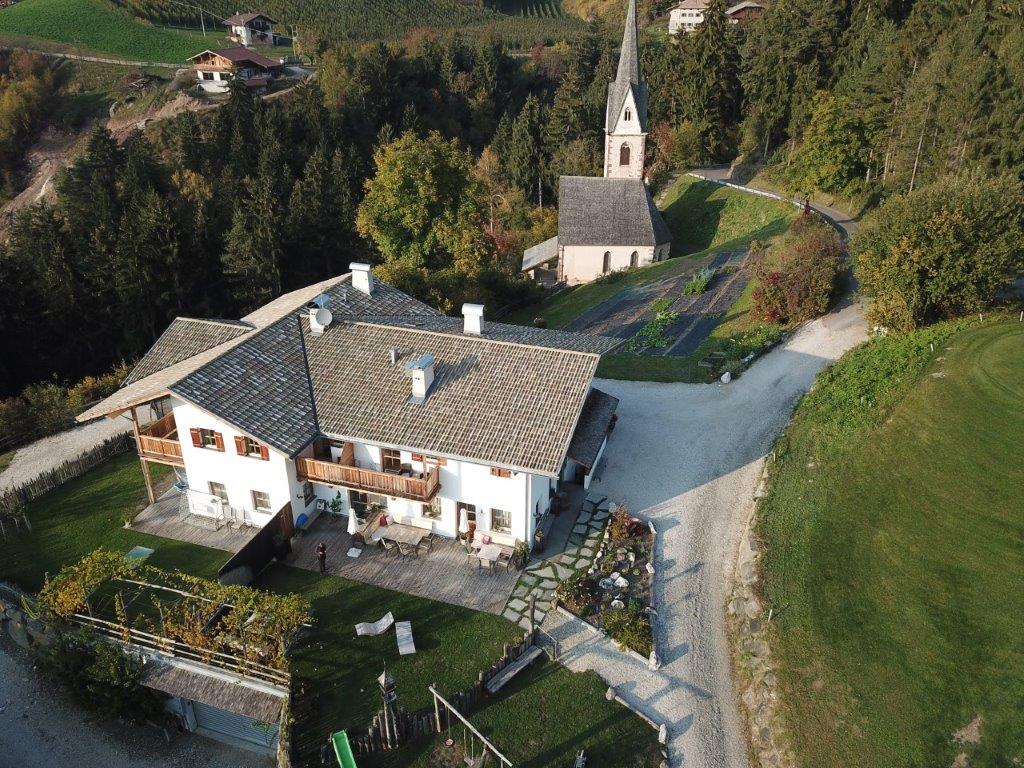 Aerial view of the Örtlhof with the church St. Vigil of Seis in the background